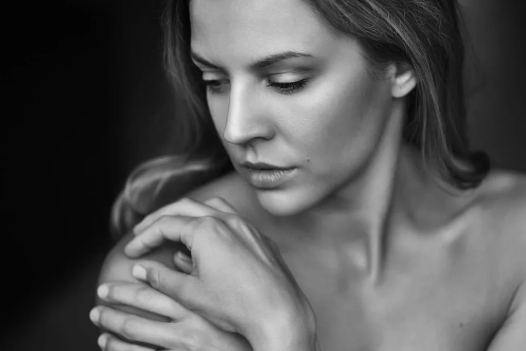 Mujer en blanco y negro abrazándose, mostrando hombros y manos, como parte de la sección de cuidado facial Zinzino